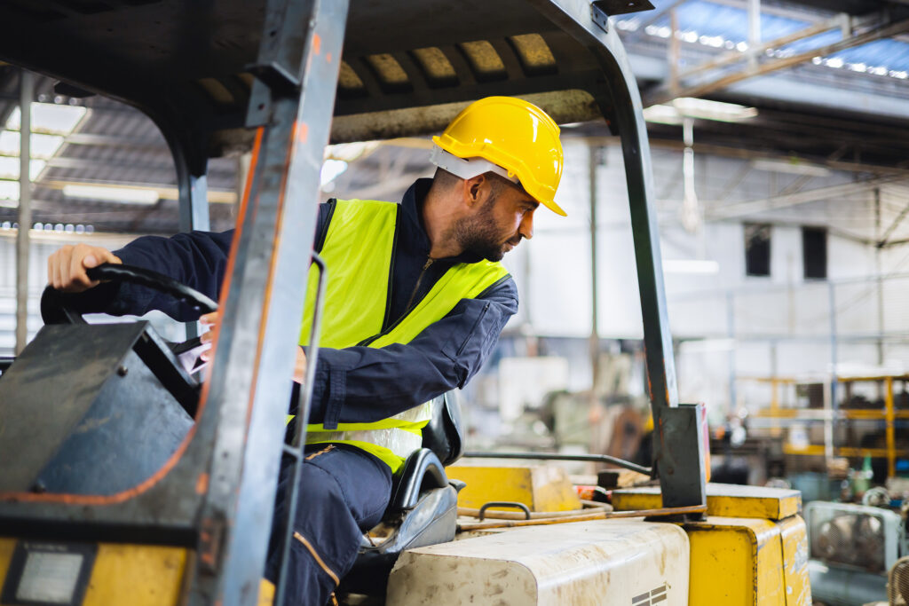 A forklift operator looks behind him as he backs up. Awareness of potential struck-by hazards is critical in solar construction and distribution work.