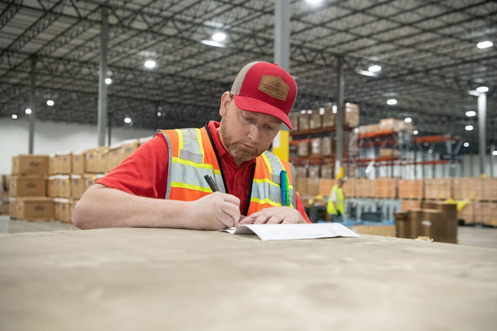 Team member completing paperwork in an Ampacity warehouse supporting renewable energy and electrical infrastructure projects.