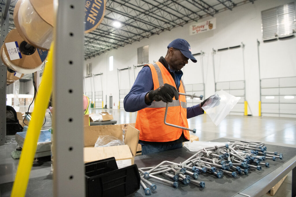 Ampacity team member preparing row box components by sorting, labeling, and packaging materials for solar projects.